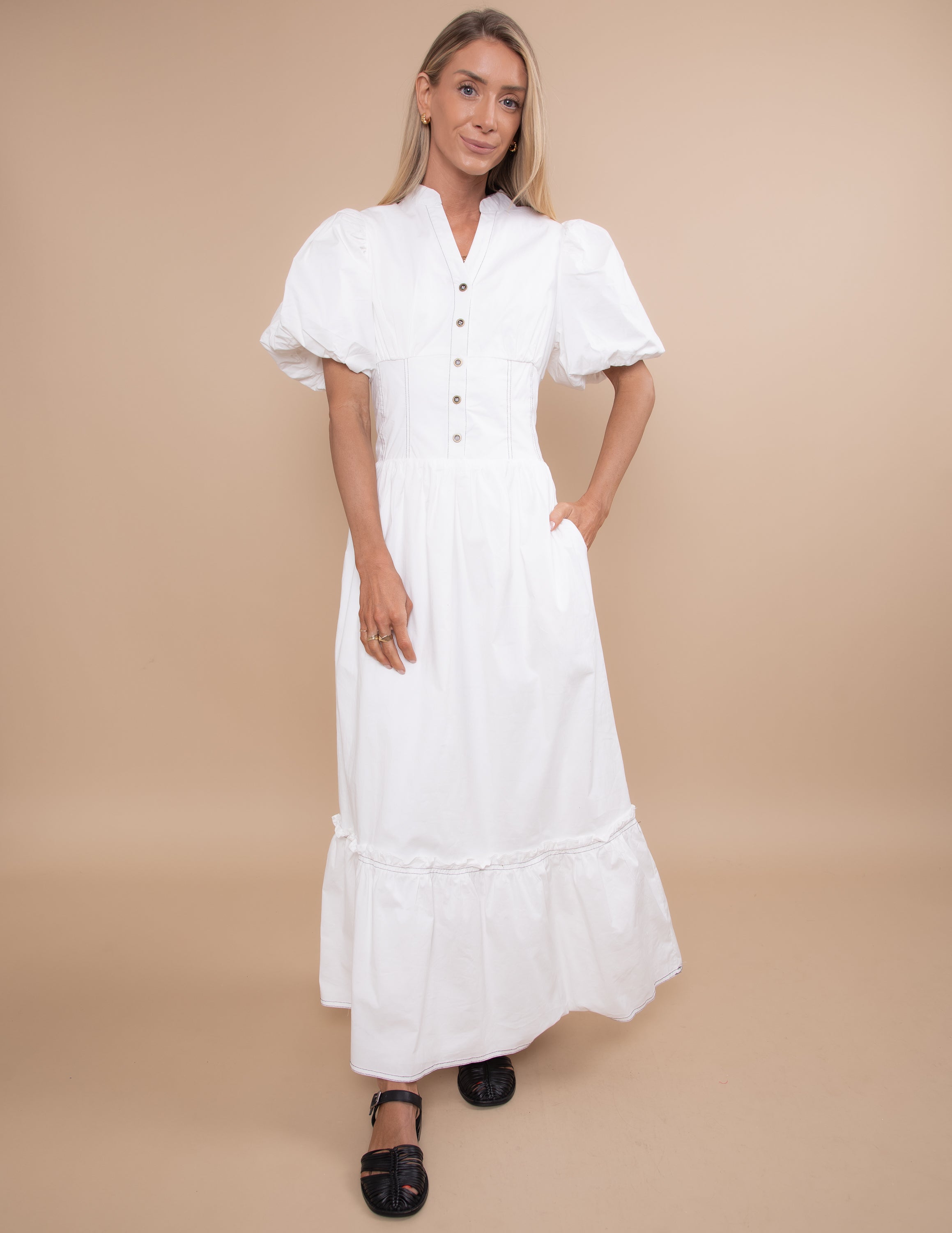 Woman wearing a white dress against a beige background